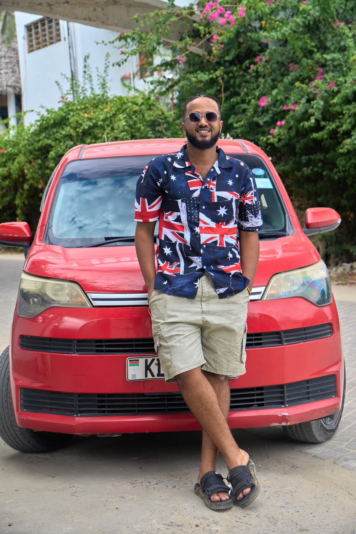 Driver standing in front of a red taxi vehicle for Mombasa tours and coastal transfers